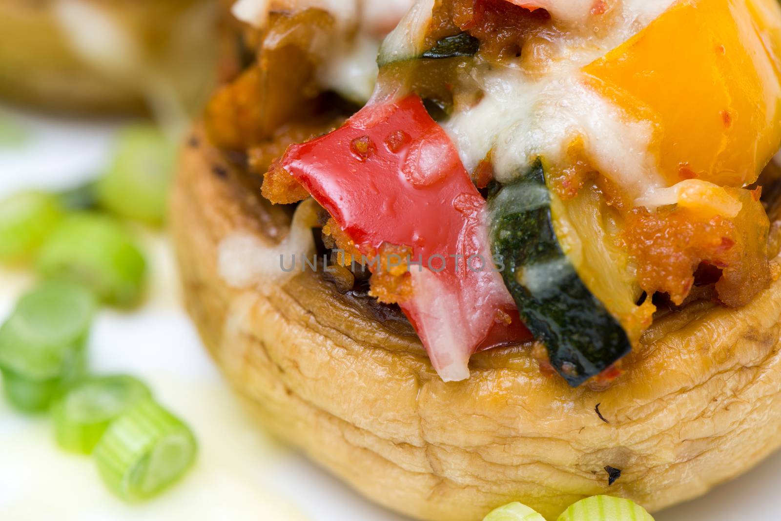 Mushrooms stuffed with vegetables and cheese on white plate fork and knife