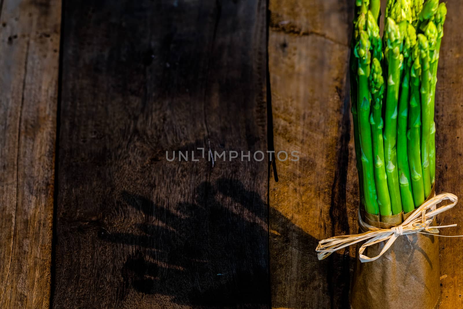 Bunch of fresh green asparagus spears tied om wood table