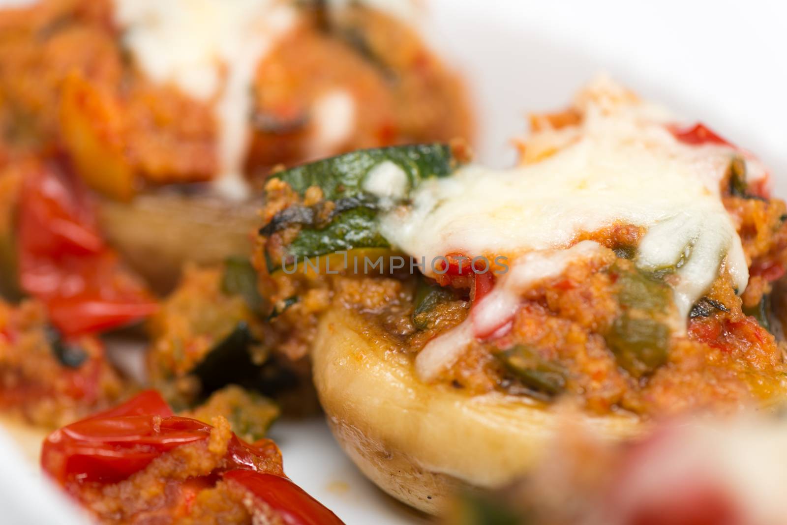 Mushrooms stuffed with vegetables and cheese on white plate