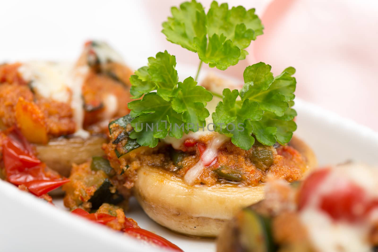 Mushrooms stuffed with vegetables and cheese on white plate