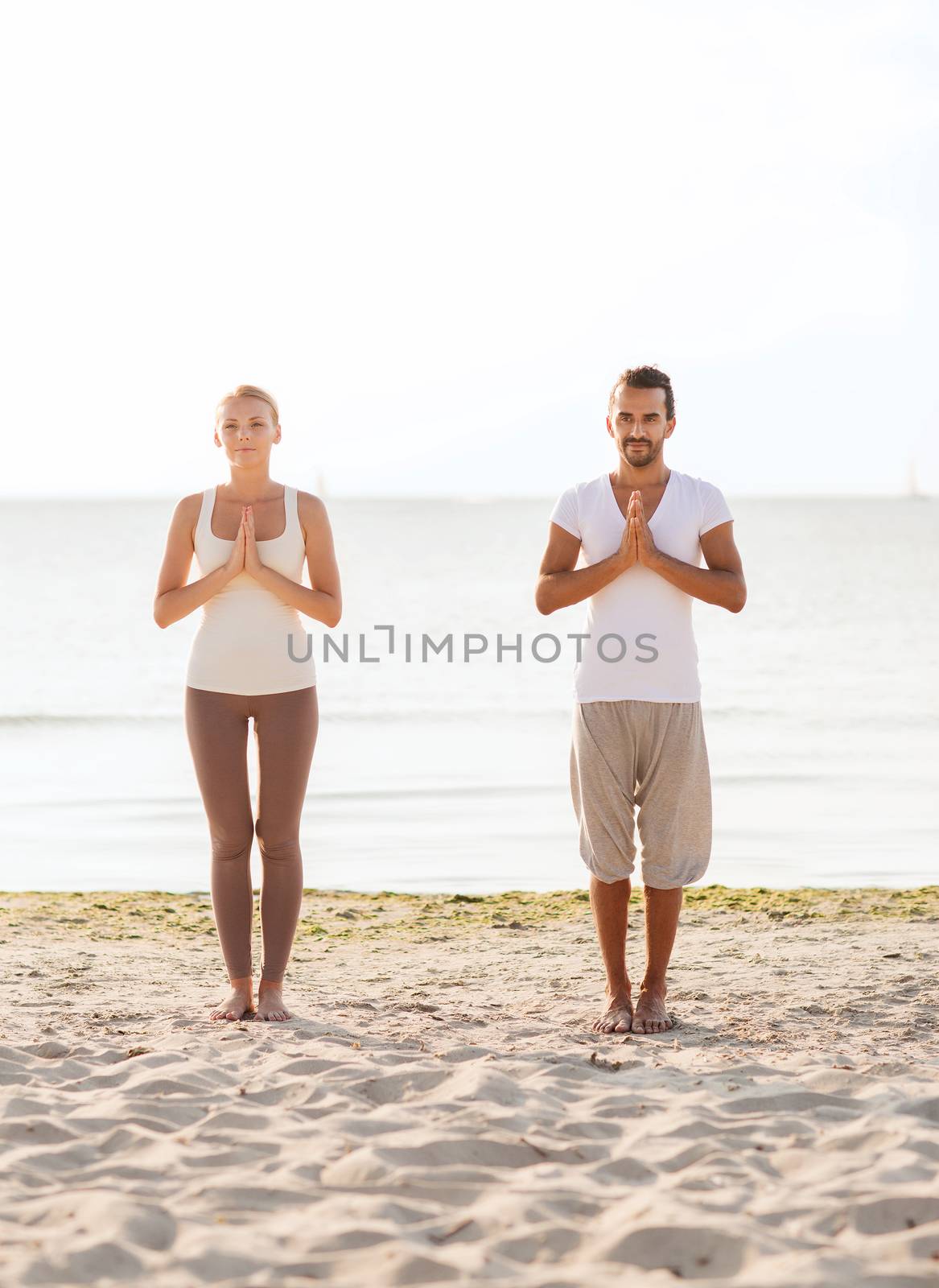 couple making yoga exercises outdoors by dolgachov