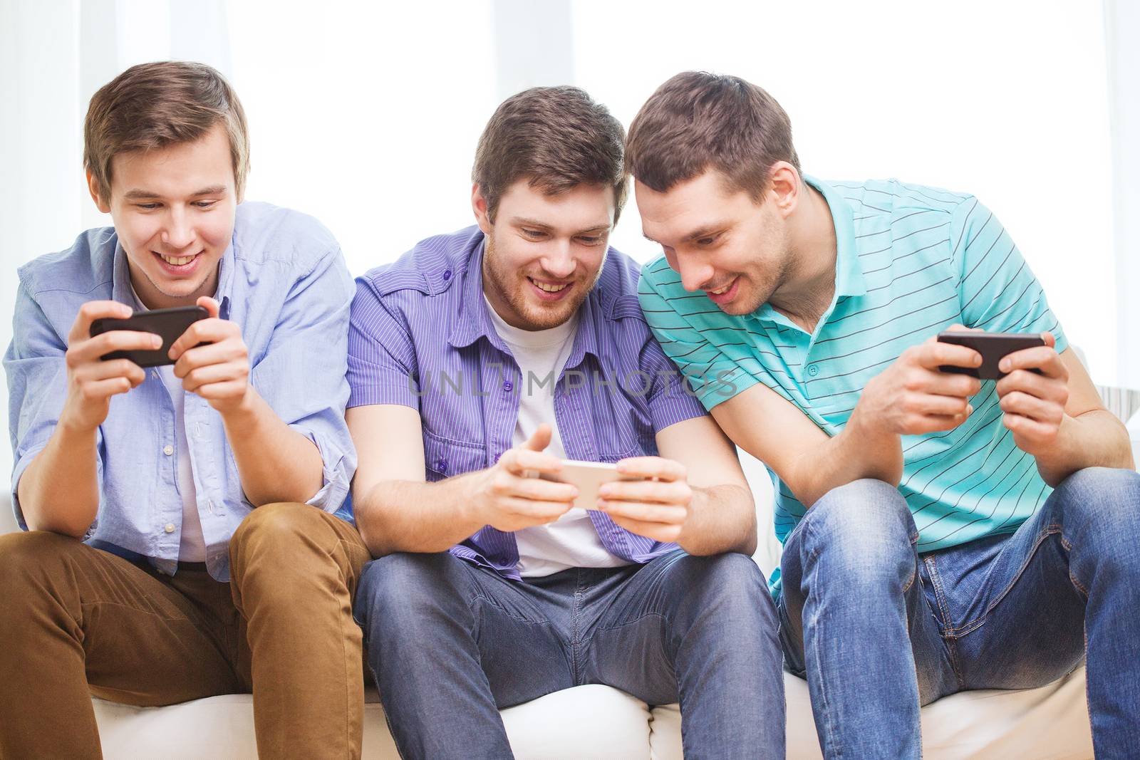 friendship, technology and home concept - smiling male friends with smartphones at home