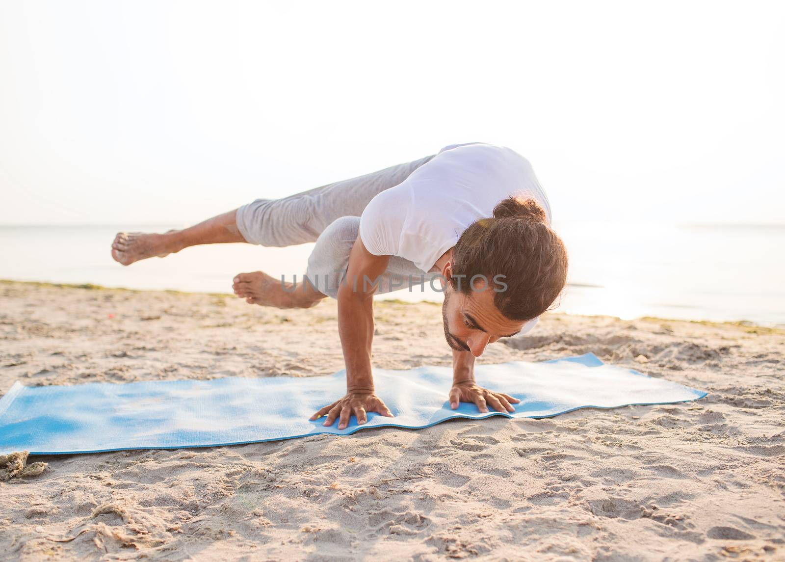 man doing yoga exercises outdoors by dolgachov