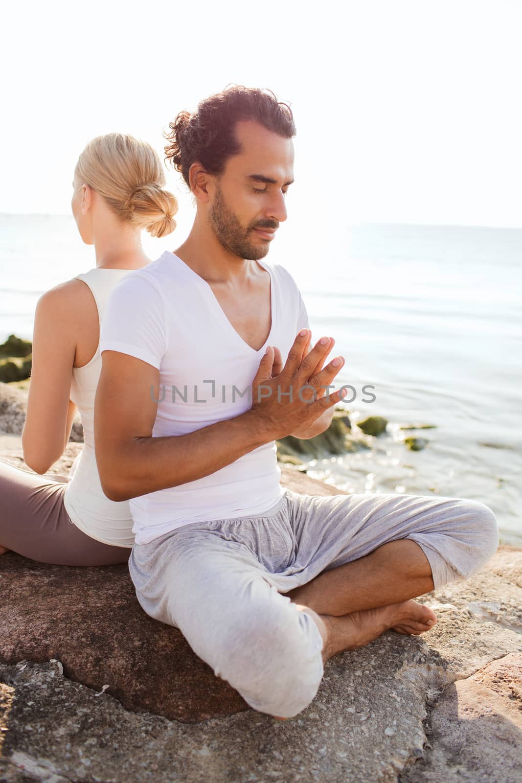 smiling couple making yoga exercises outdoors by dolgachov