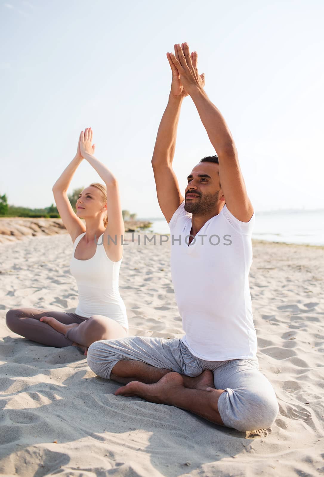 smiling couple making yoga exercises outdoors by dolgachov