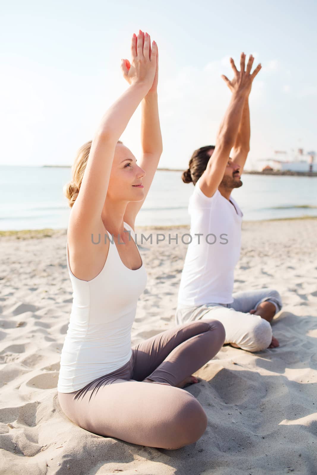 smiling couple making yoga exercises outdoors by dolgachov