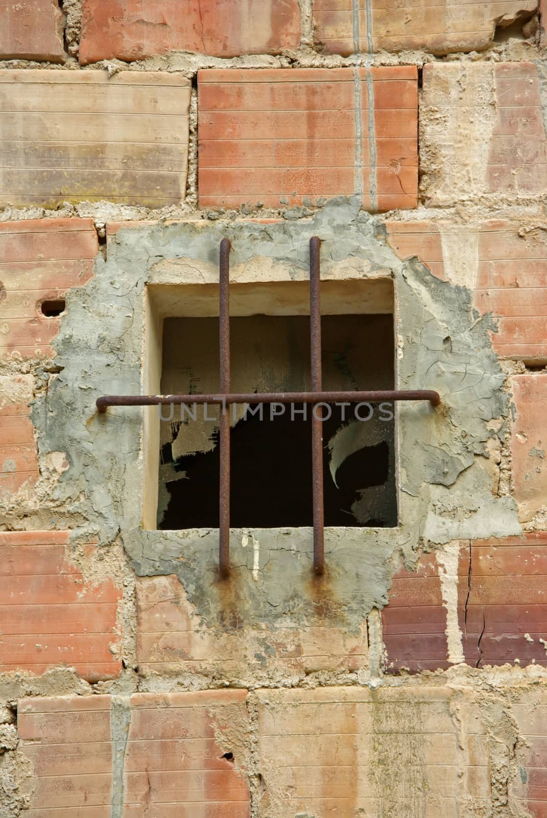 Old window in a brick wall protected with a grid of iron bars