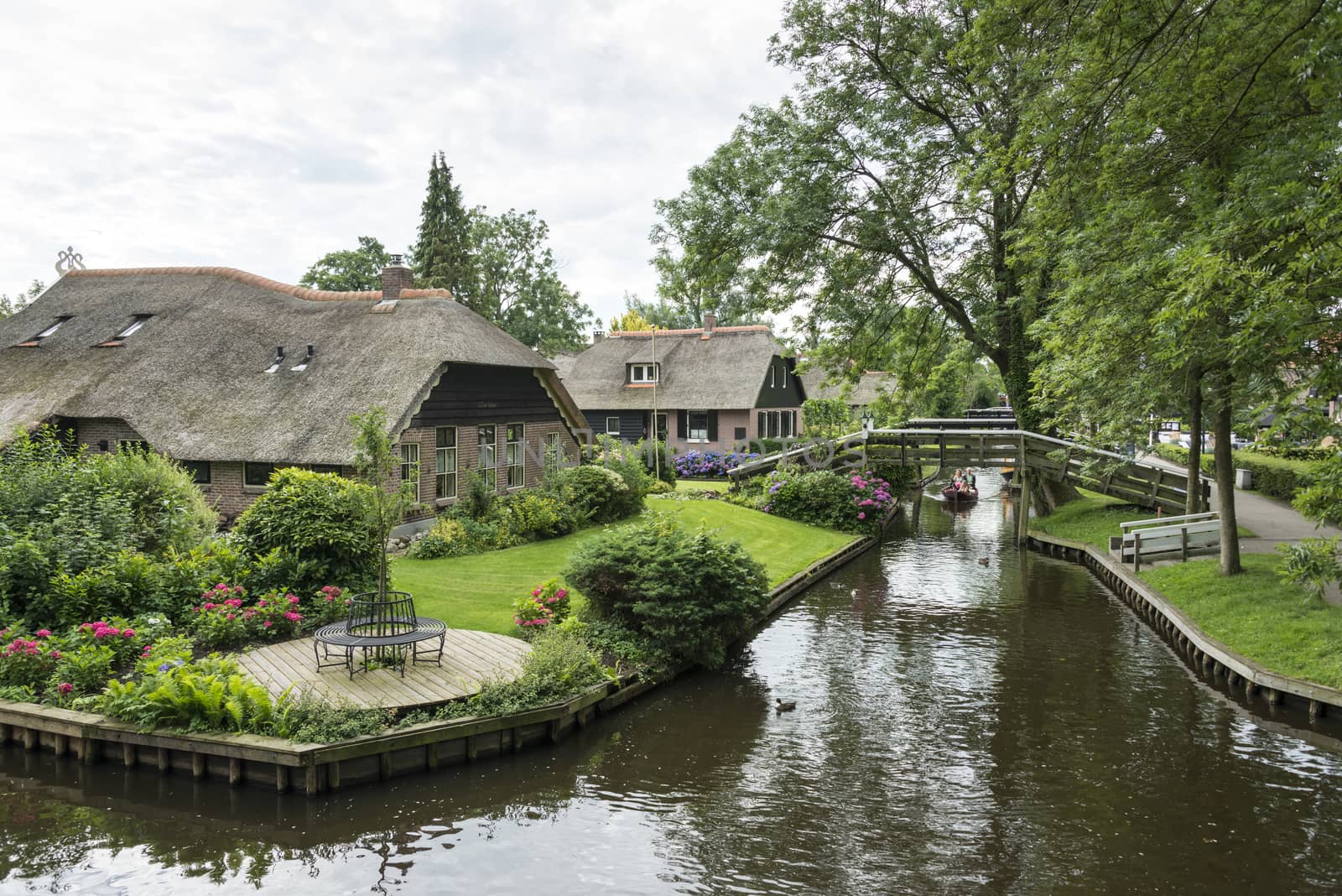 GIETHOORN, NETHERLANDS - JULY 18, 2015: Unknown tourists on boating trip in a canal in Giethoorn on july 18 2015. The beautiful houses and gardening city is know as "Venice of the North"