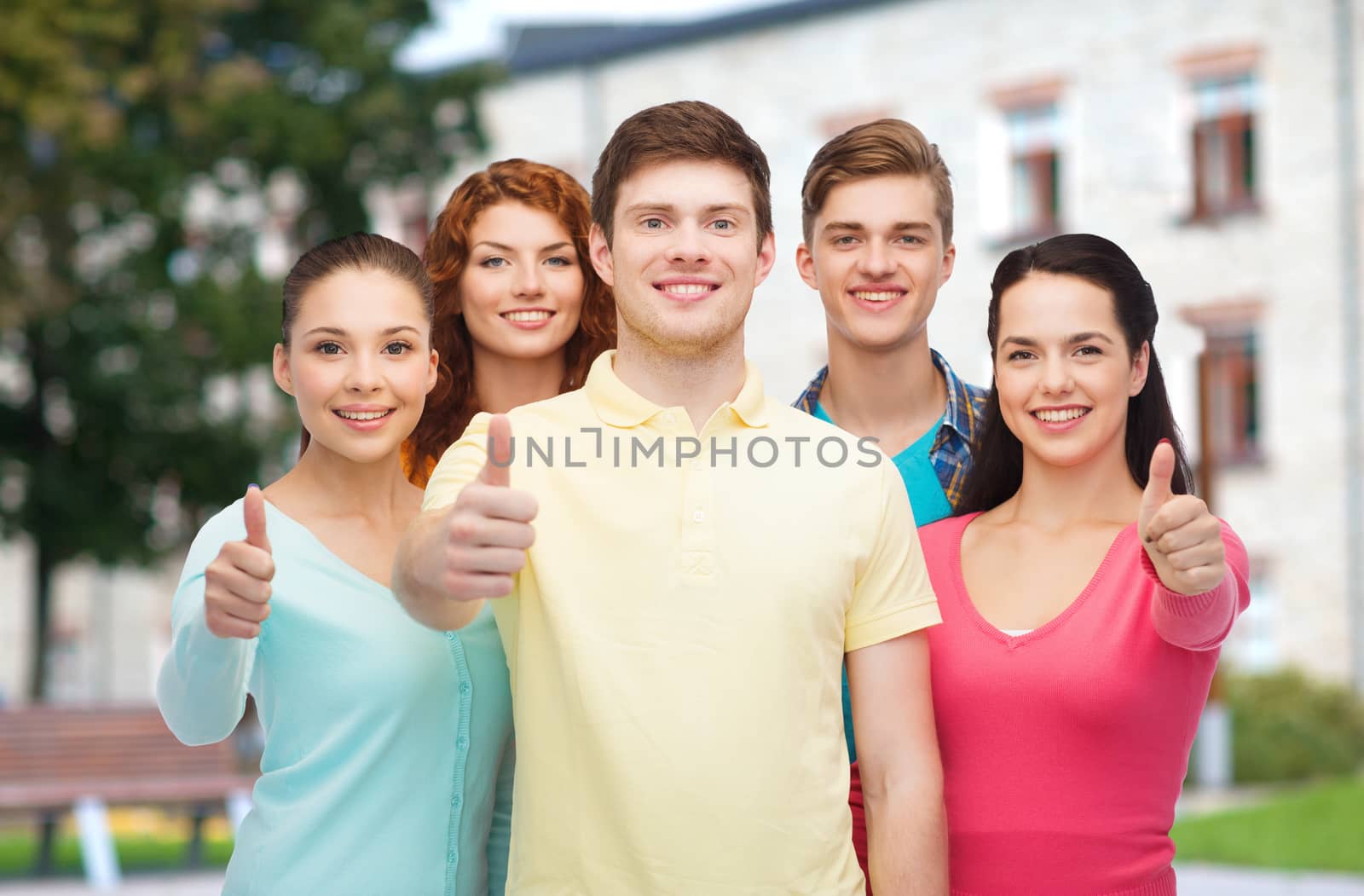 group of smiling teenagers over campus background by dolgachov