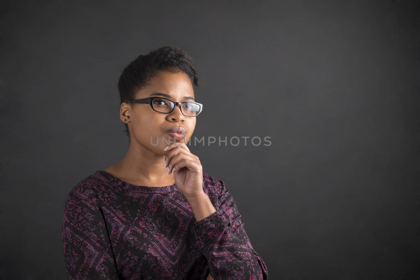 African woman with hand on chin thinking on blackboard background by alistaircotton