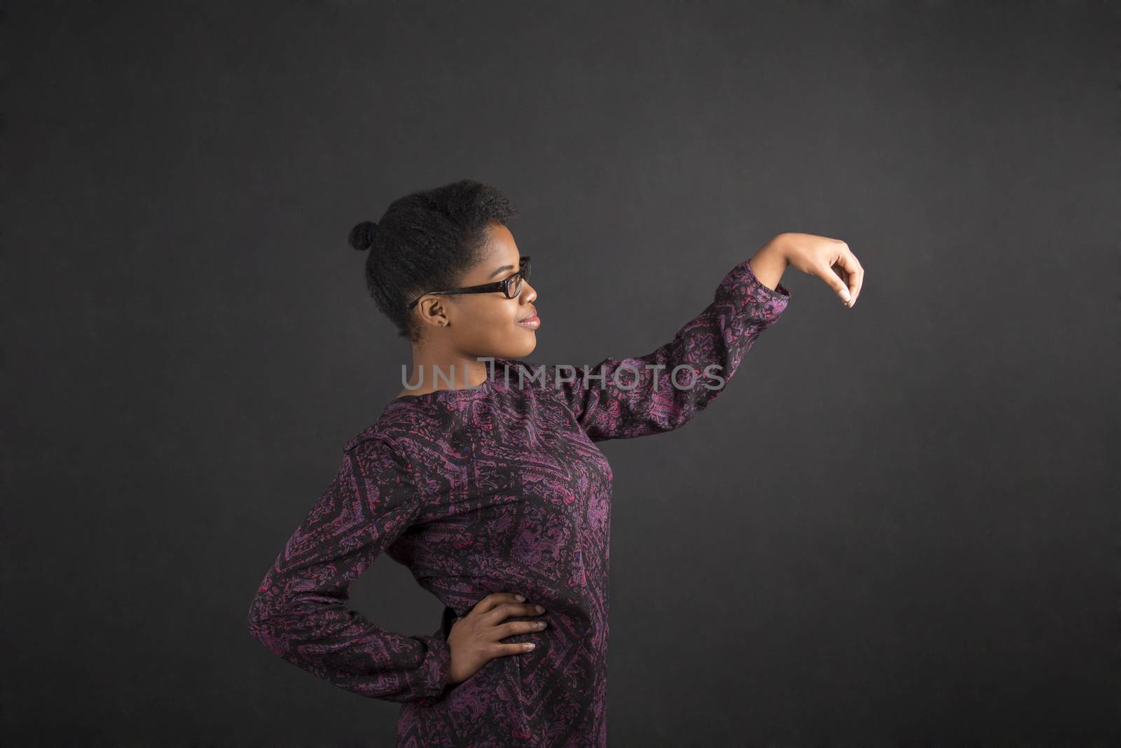 African woman holding object out to side on blackboard background by alistaircotton