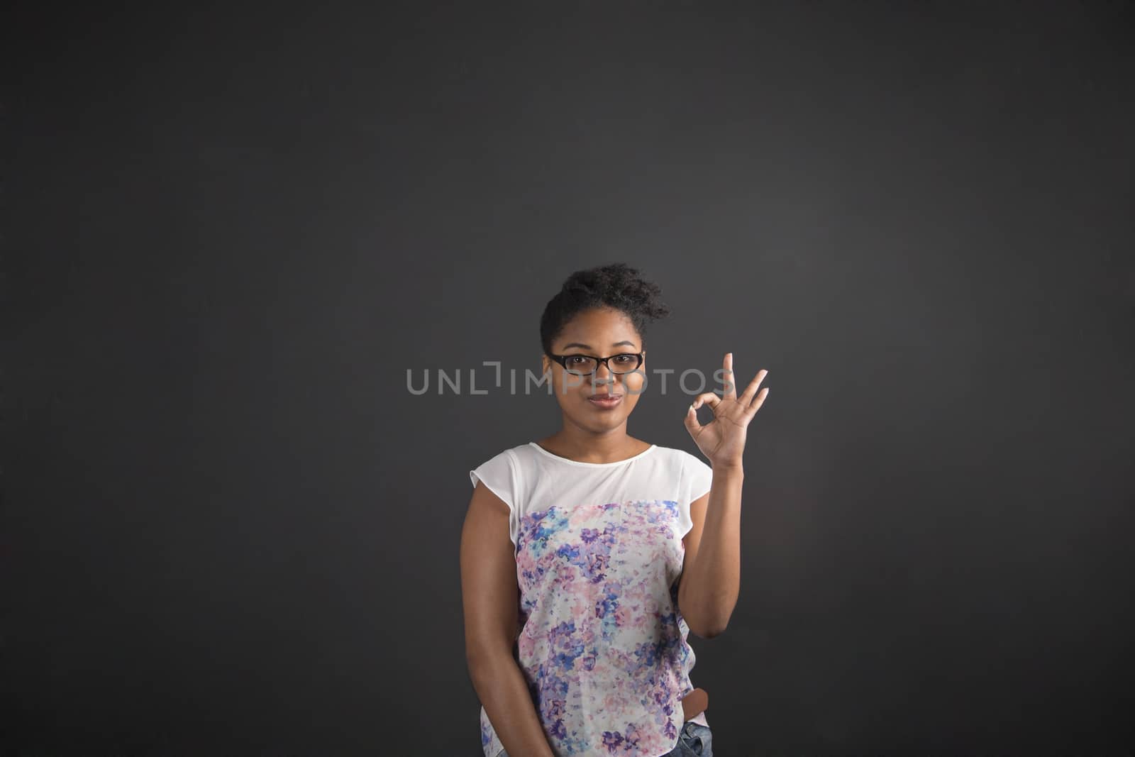 African woman with perfect hand signal on blackboard background by alistaircotton