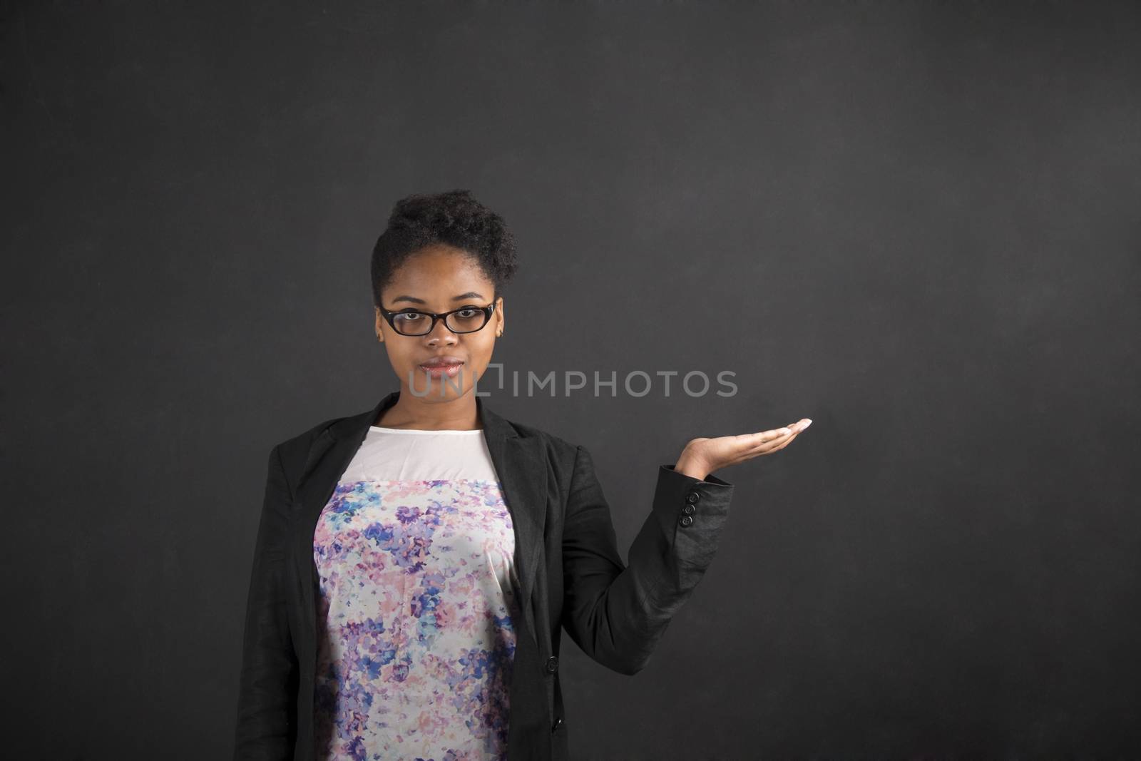 African woman holding hand out on blackboard background by alistaircotton