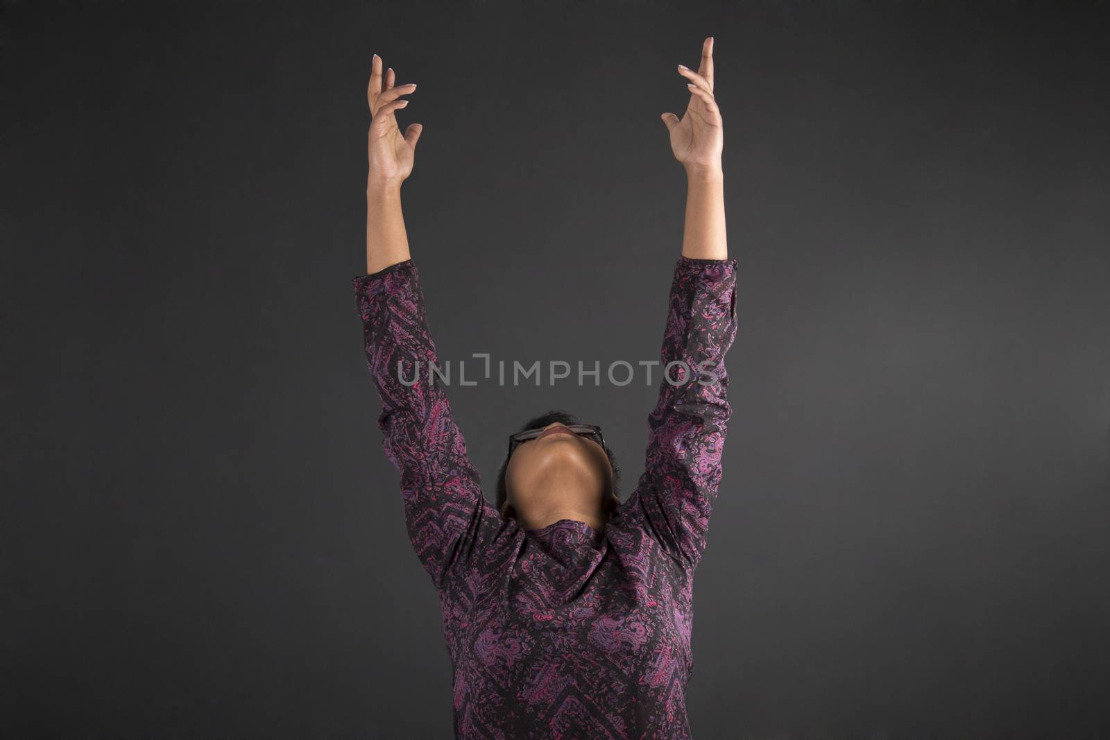 South African or African American woman teacher or student reaching for the sky on blackboard background by alistaircotton