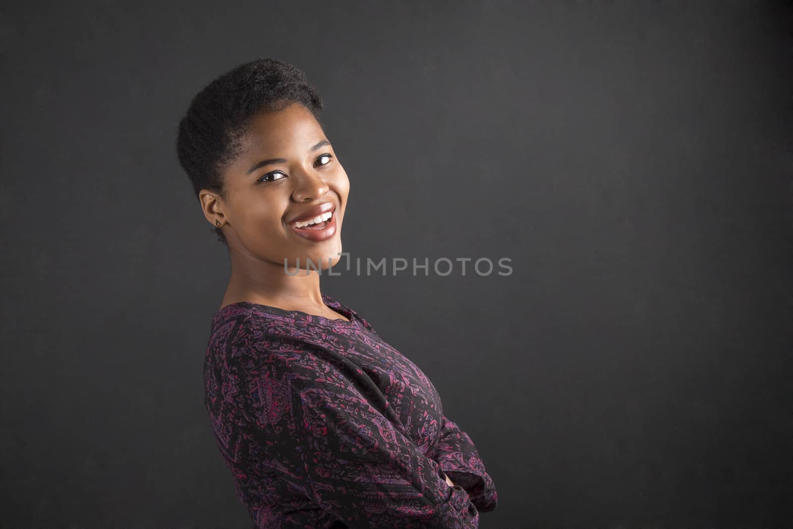 South African or African American woman teacher or student with arms folded on chalk black board background