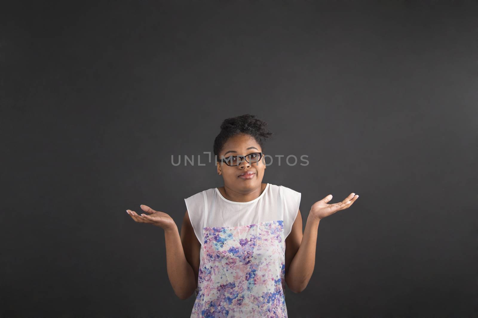 South African or African American black woman teacher or student posing with an "I don't know" gesture on a chalk blackboard background inside