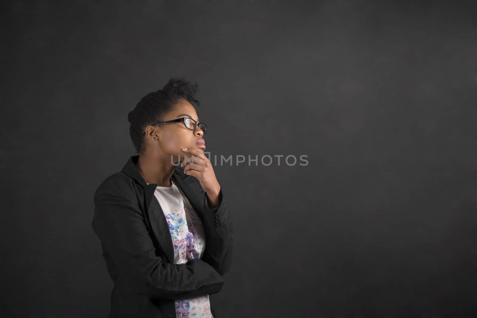 African woman with hand on chin thinking on blackboard background by alistaircotton