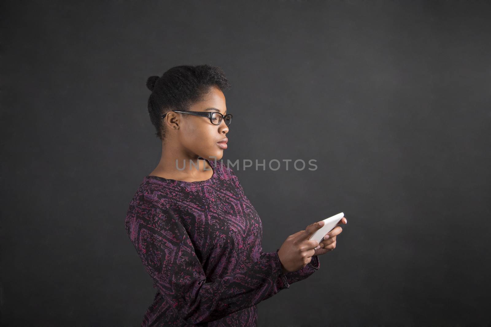 African woman with tablet on blackboard background by alistaircotton