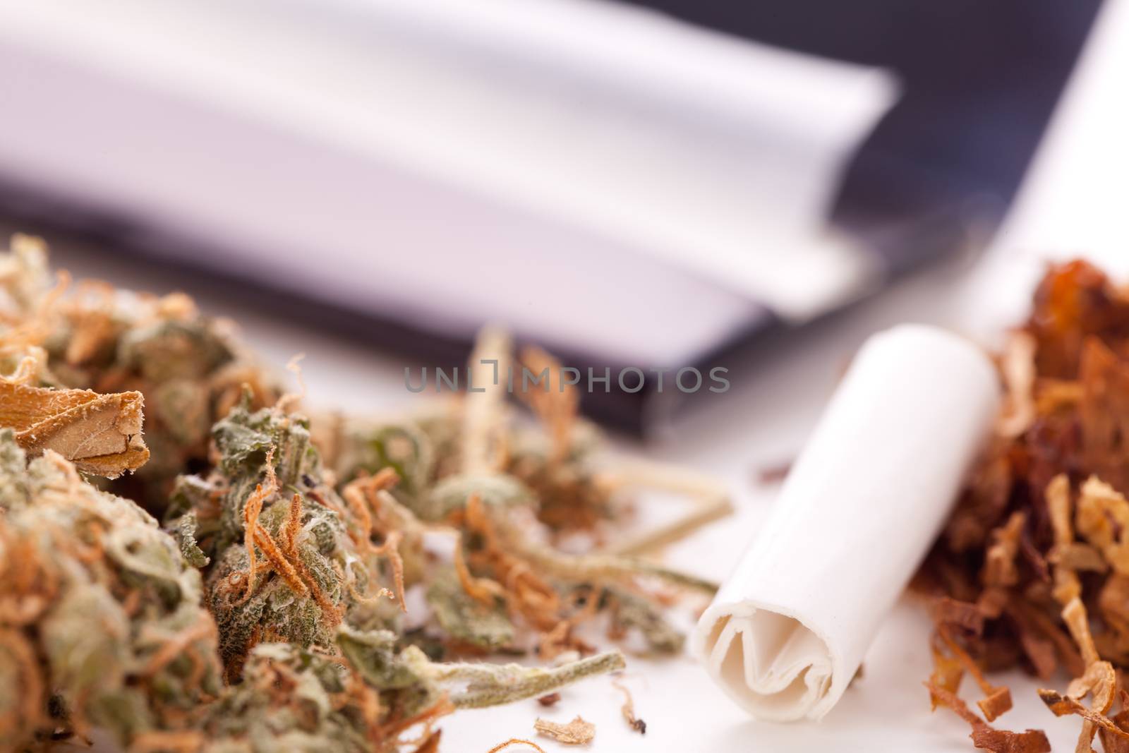 Close up Dried Cannabis Leaves on a Resealable Cellophane Wrapper and a Rolling Paper with Filter on Top of the Table