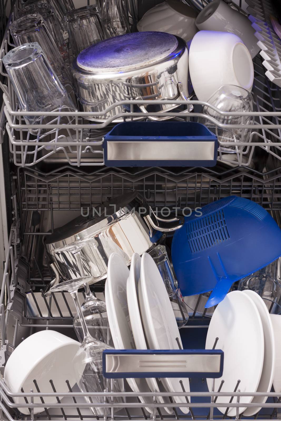 Dishwasher loades in a kitchen with clean dishes by juniart