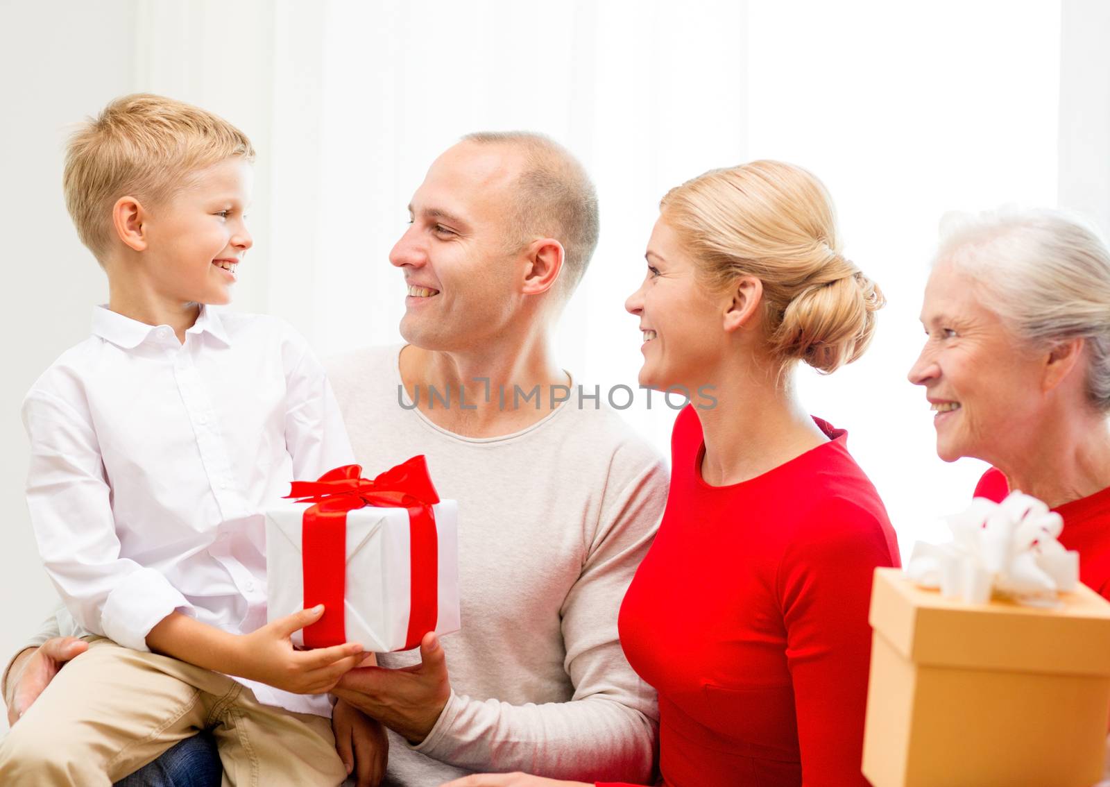 family, holidays, generation, christmas and people concept - smiling family with gift boxes sitting on couch at home