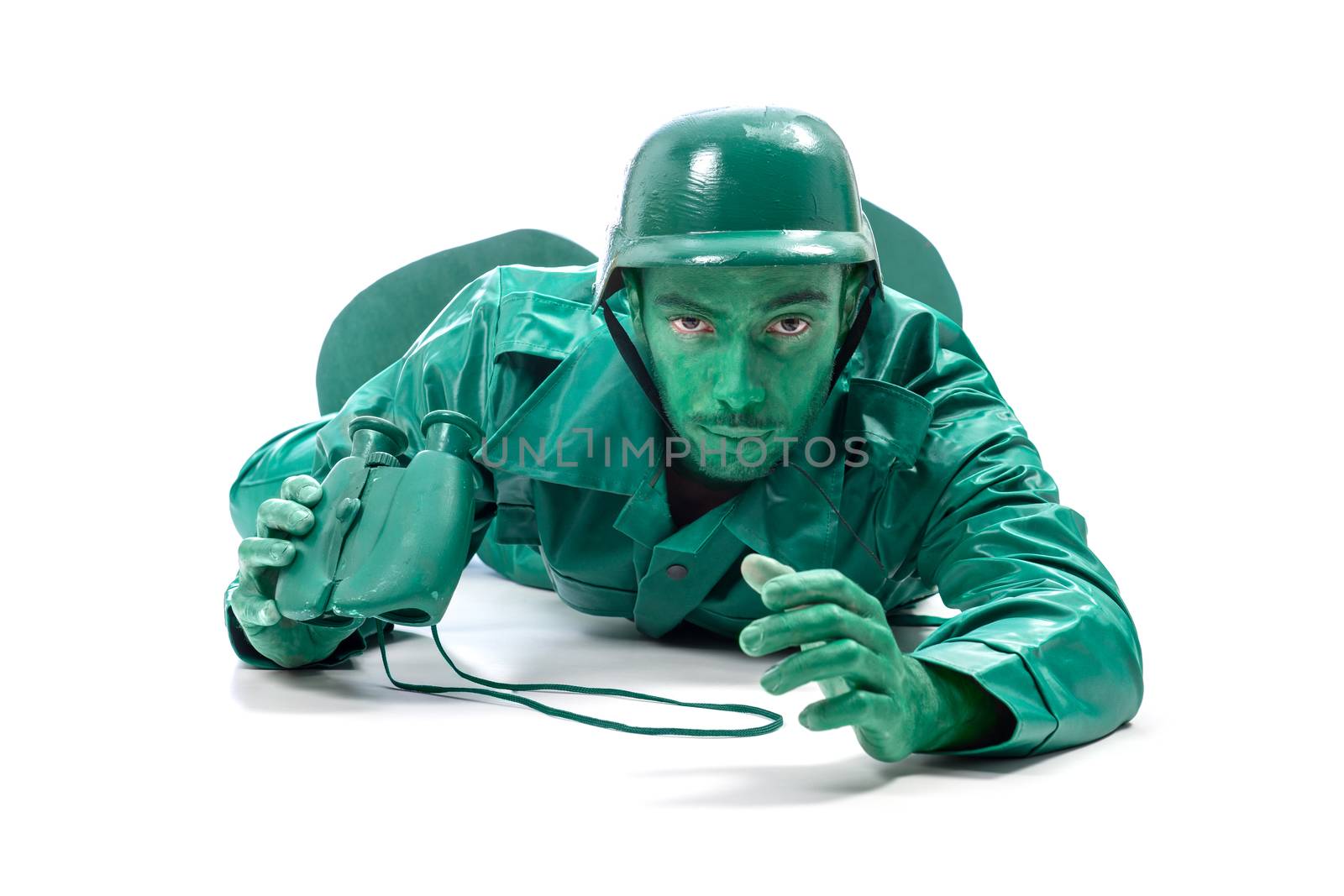 Man on a green toy soldier costume, crawling with binocolous isolated on white background.