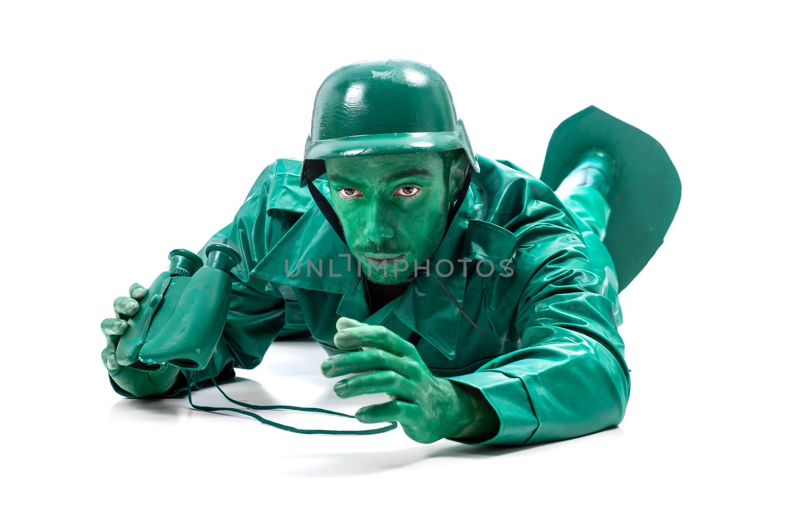 Man on a green toy soldier costume, crawling with binocolous isolated on white background.