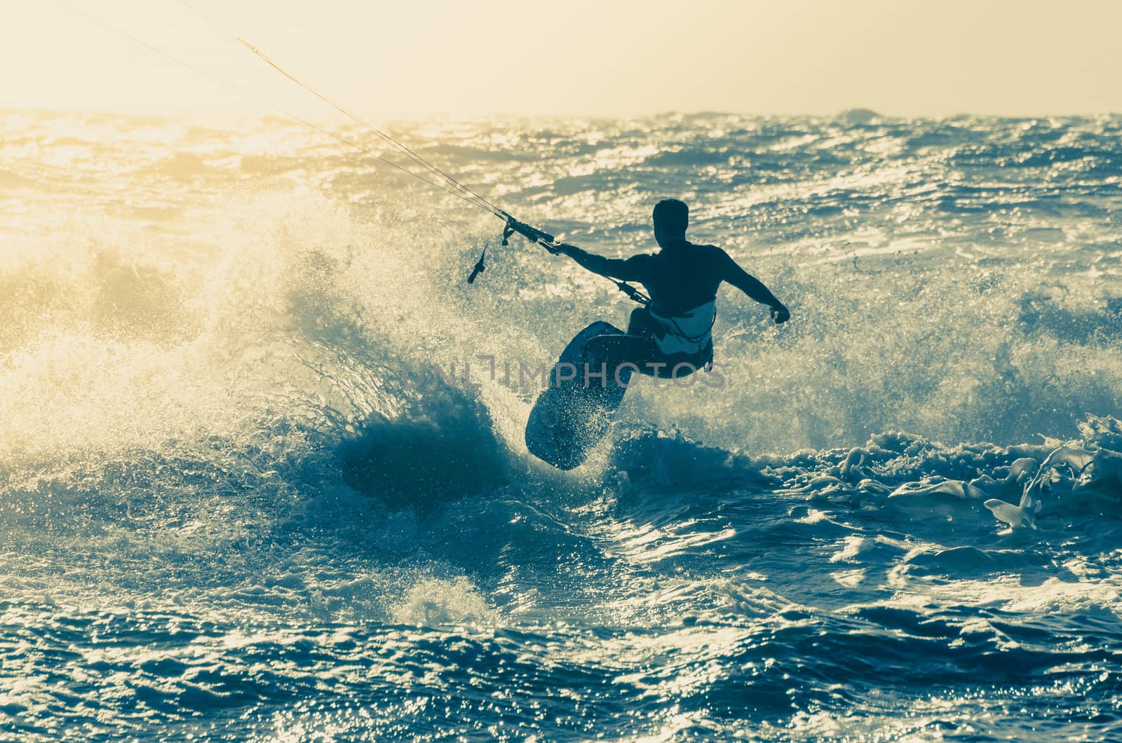 Kitesurfer in action on a beautiful background of spray during the sunset.