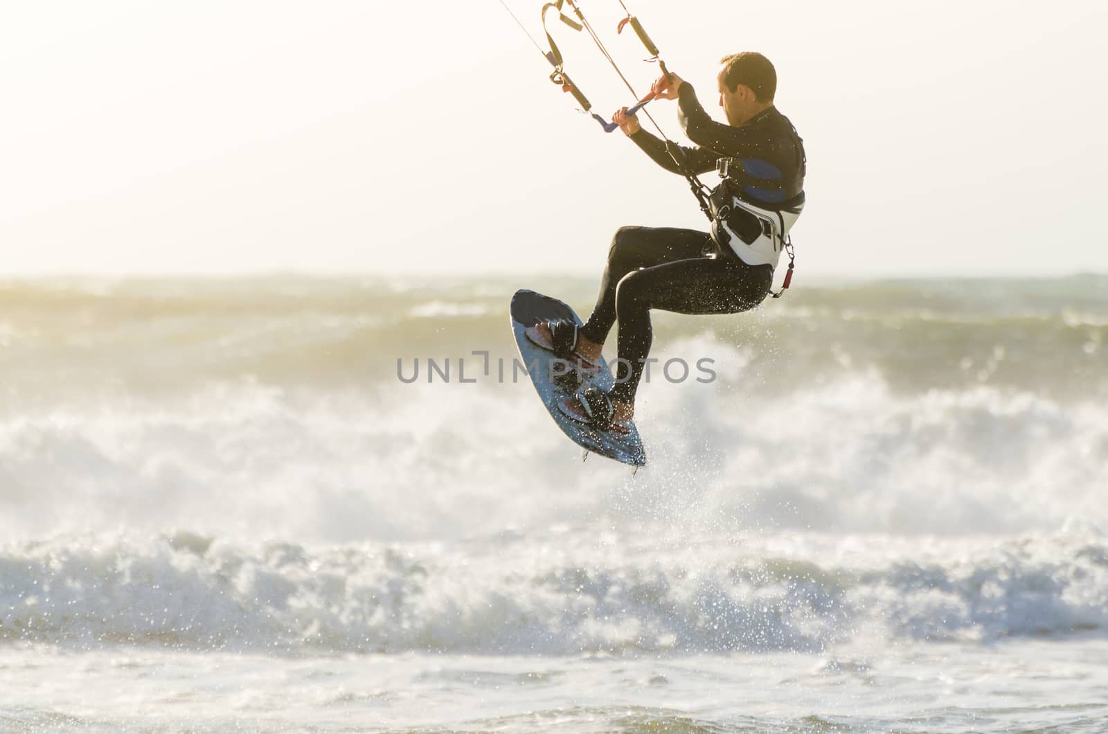 Kitesurfer jumping on a beautiful background of spray during the sunset.