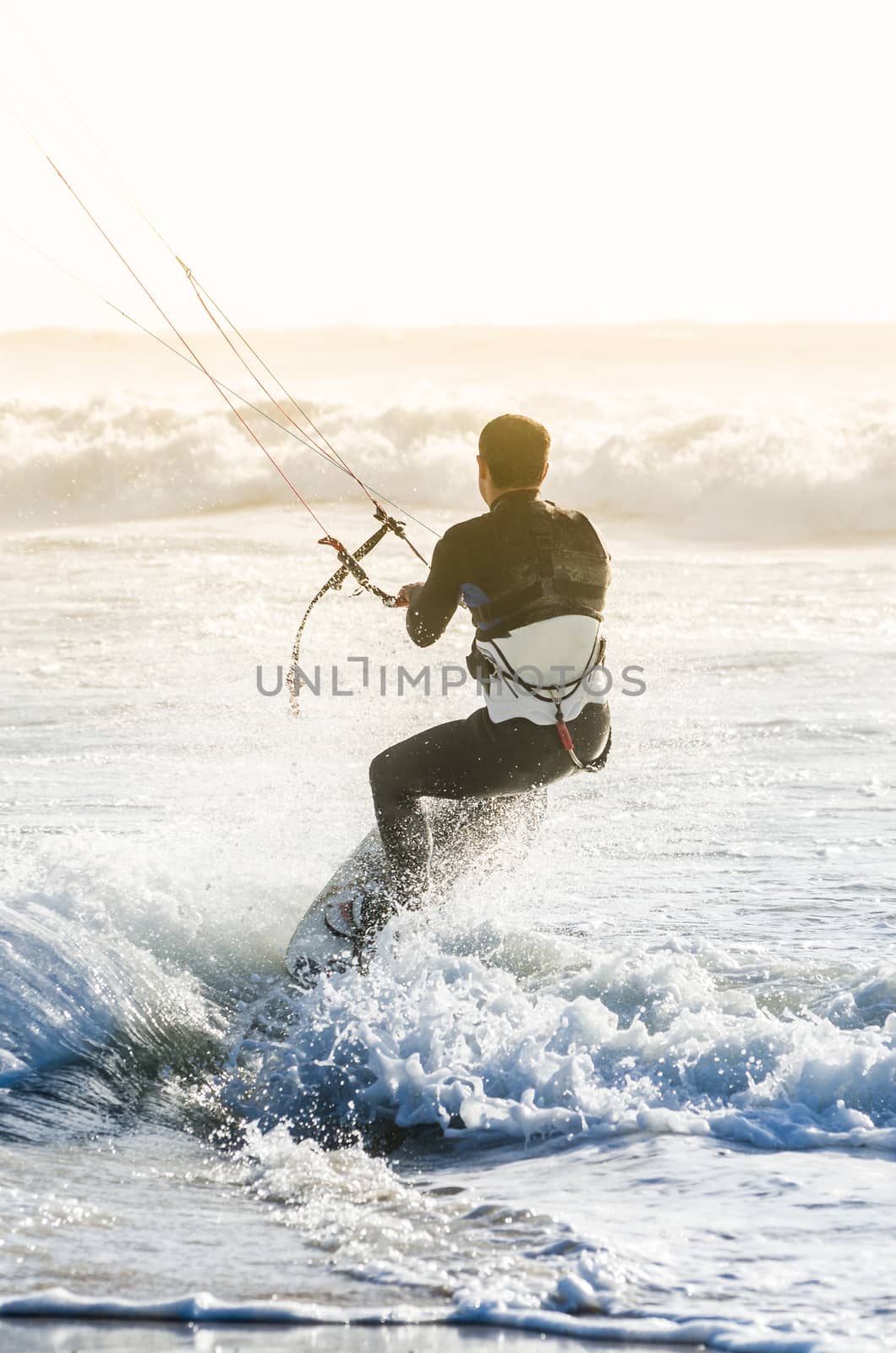 Kitesurfer in action on a beautiful background of spray during the sunset.