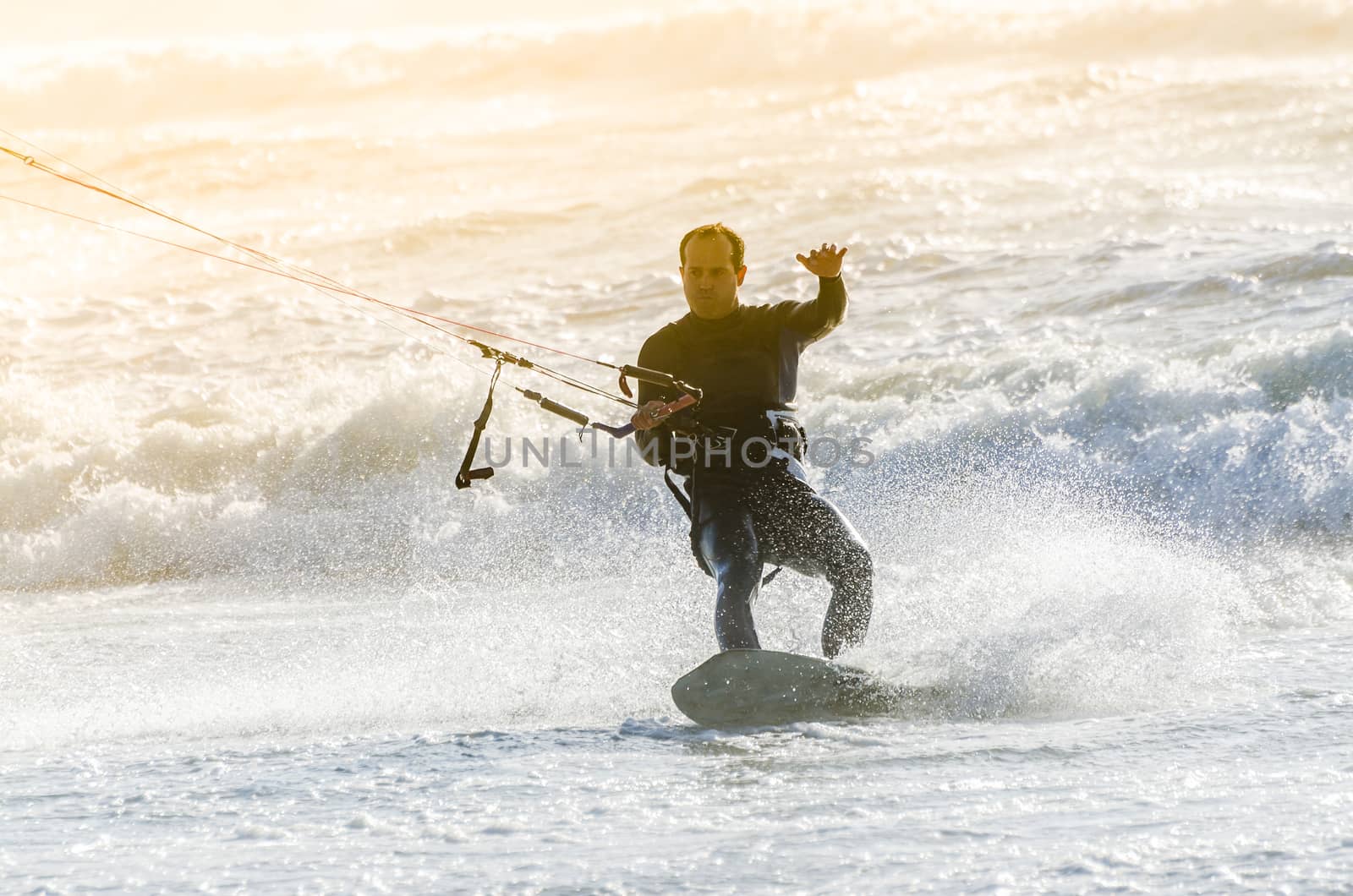 Kitesurfer in action on a beautiful background of spray during the sunset.