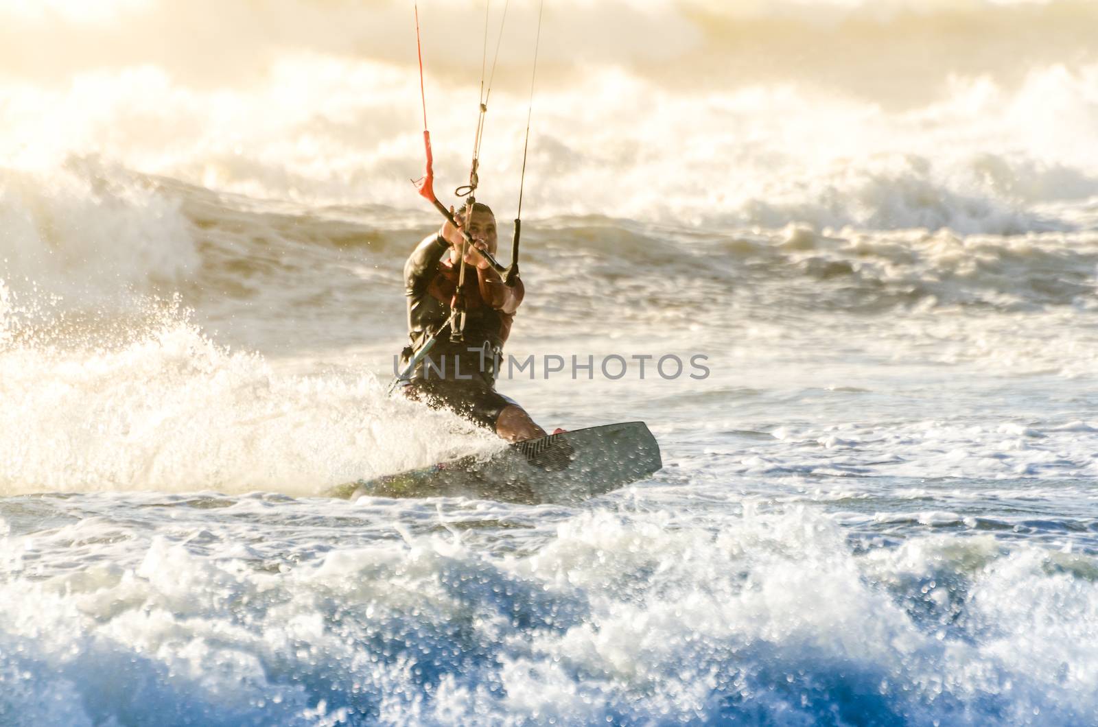 Kitesurfer in action on a beautiful background of spray during the sunset.