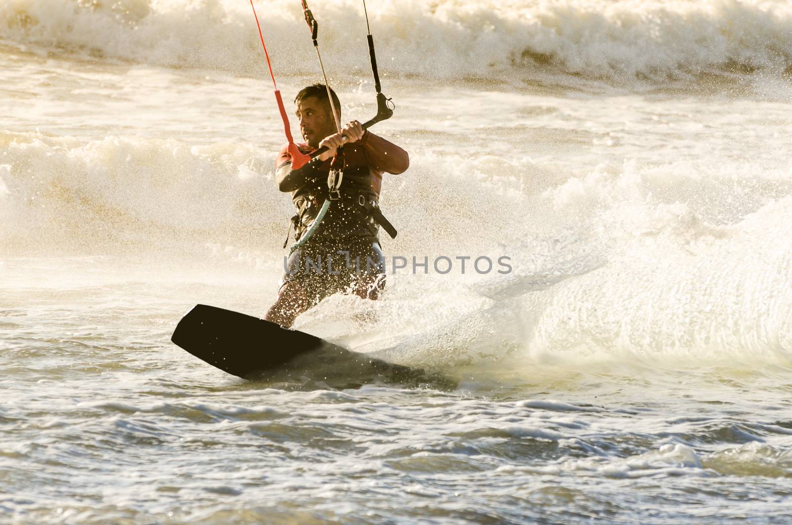 Kitesurfer in action on a beautiful background of spray during the sunset.