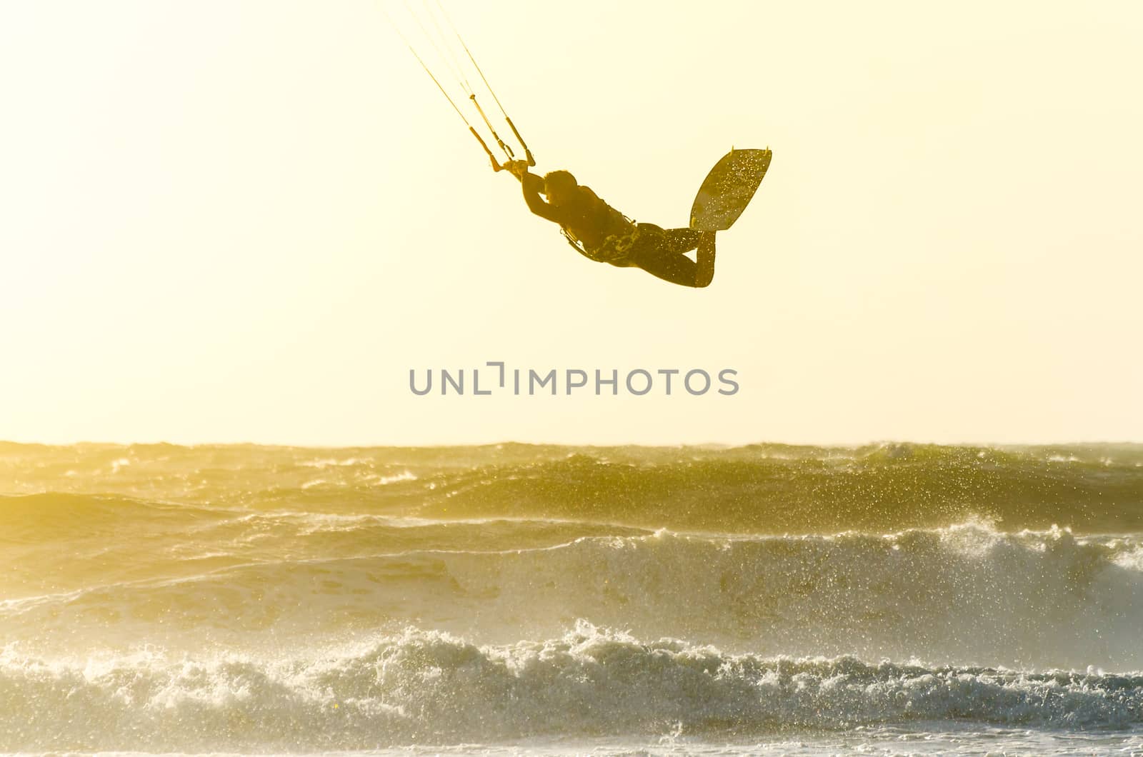 Kitesurfer jumping on a beautiful background of spray during the sunset.