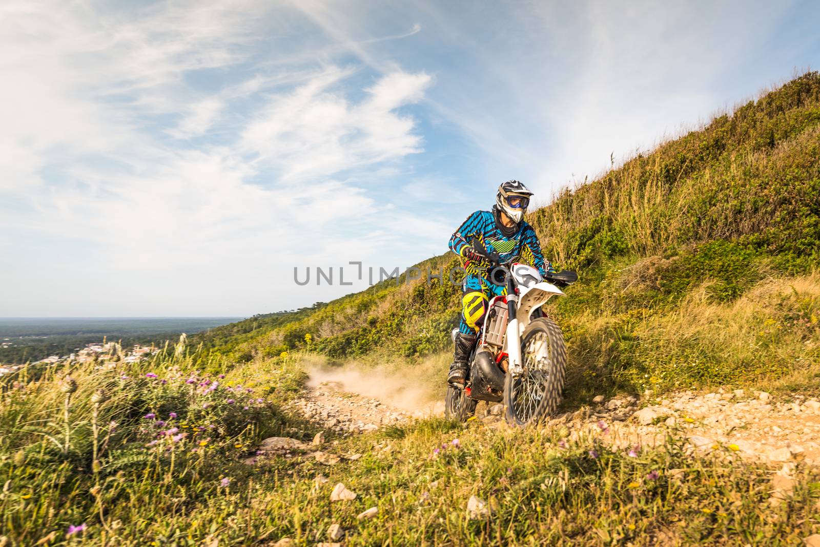 Enduro rider climbing a steep slope against a sunset sky.