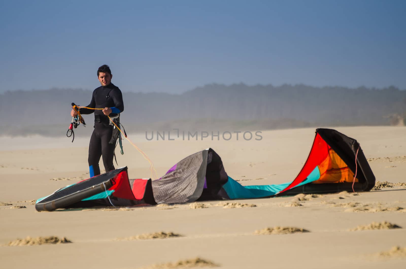 Kitesurfer prepating his equipment on a beautiful sunset at the beach.