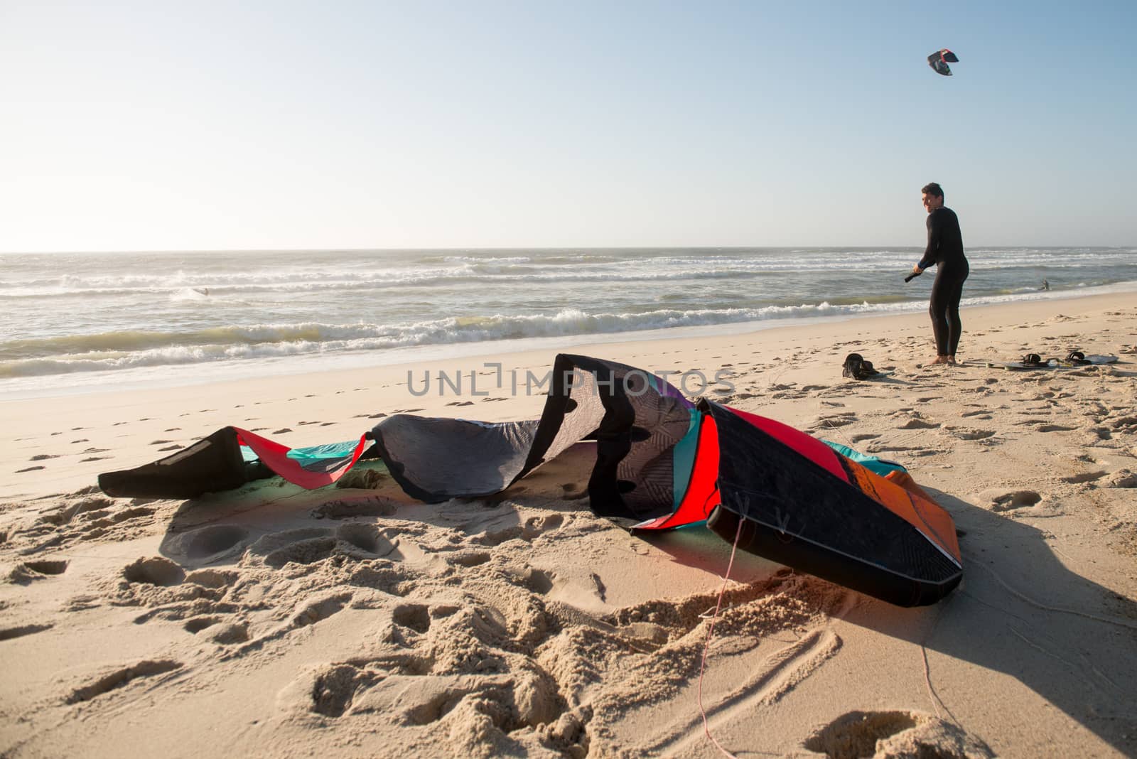 Kitesurfer prepating his equipment on a beautiful sunset at the beach.