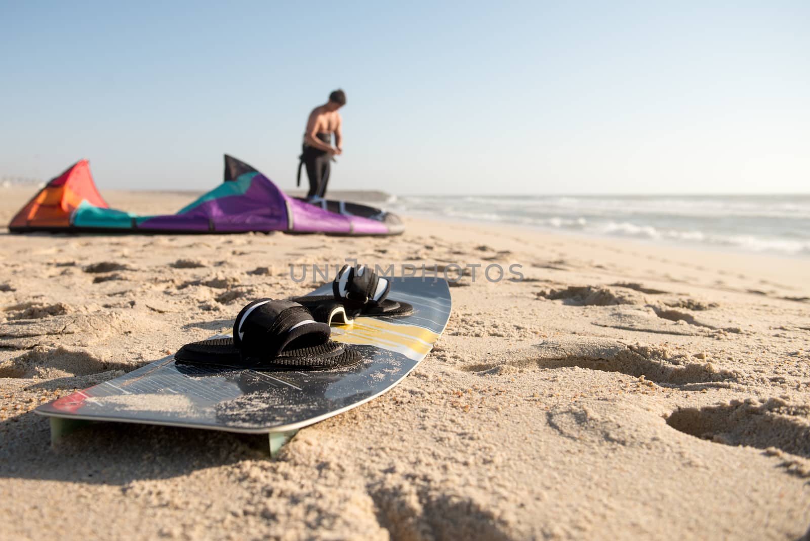 Kitesurfer prepating his equipment on a beautiful sunset at the beach.