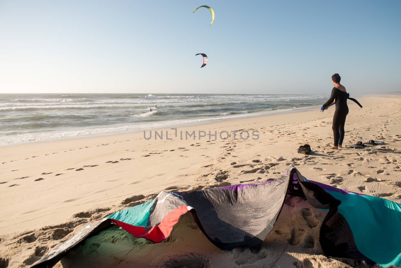 Kitesurfer prepating his equipment on a beautiful sunset at the beach.