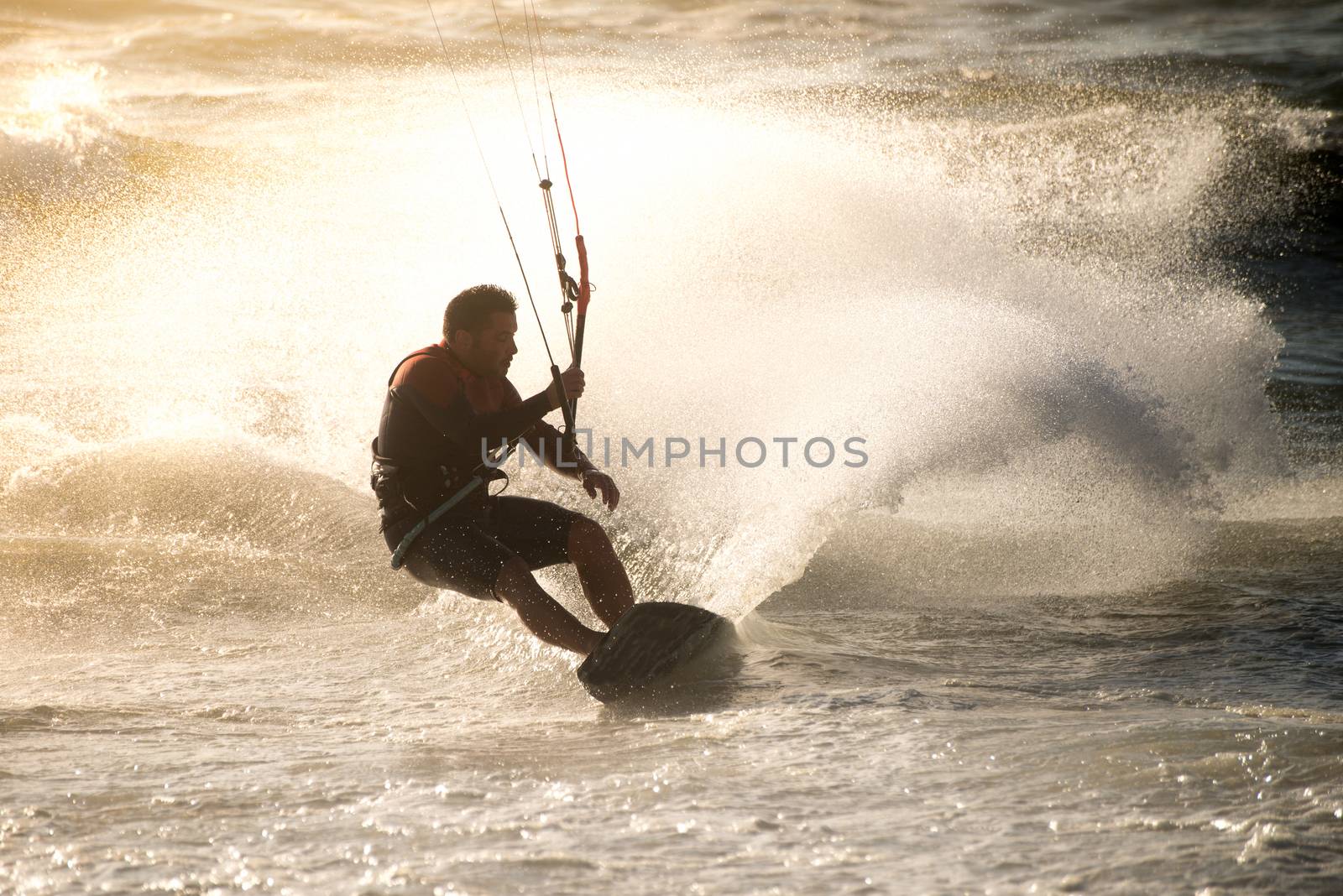 Kitesurfer in action on a beautiful background of spray during the sunset.