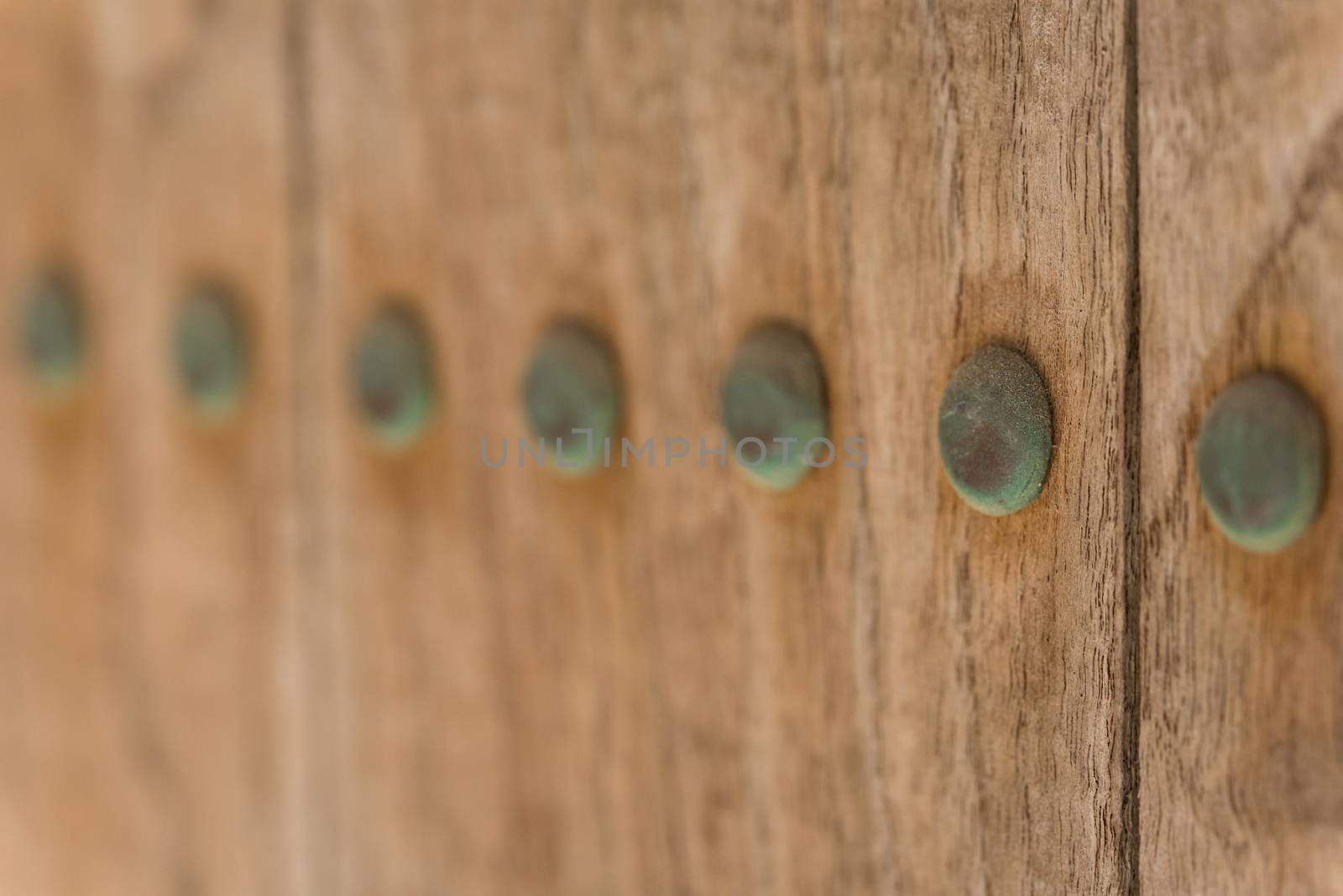 A macro shot of old copper nails which haved turned green due to oxidation on an old wooden door.