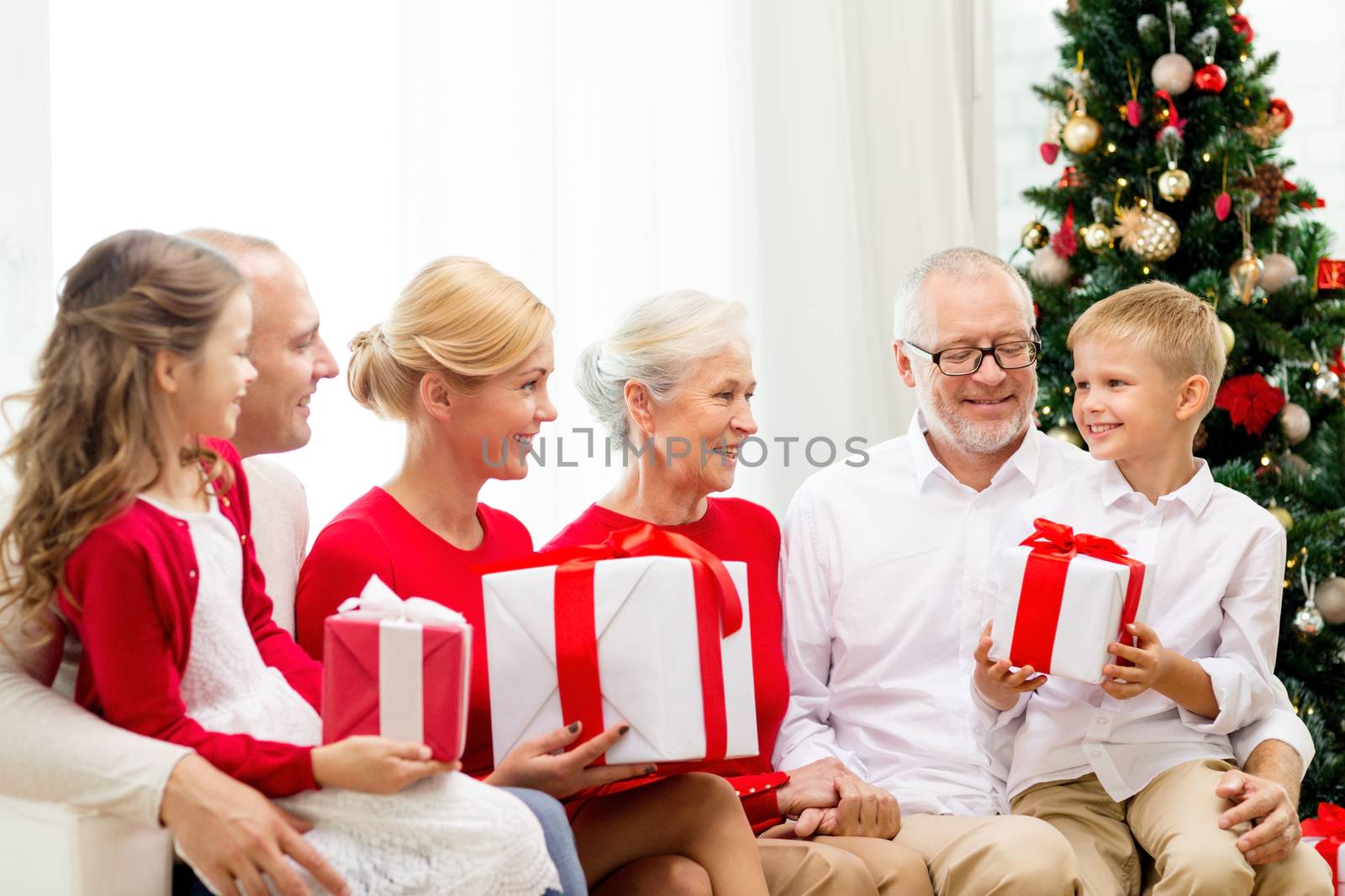 family, holidays, generation, christmas and people concept - smiling family with gift boxes sitting on couch at home