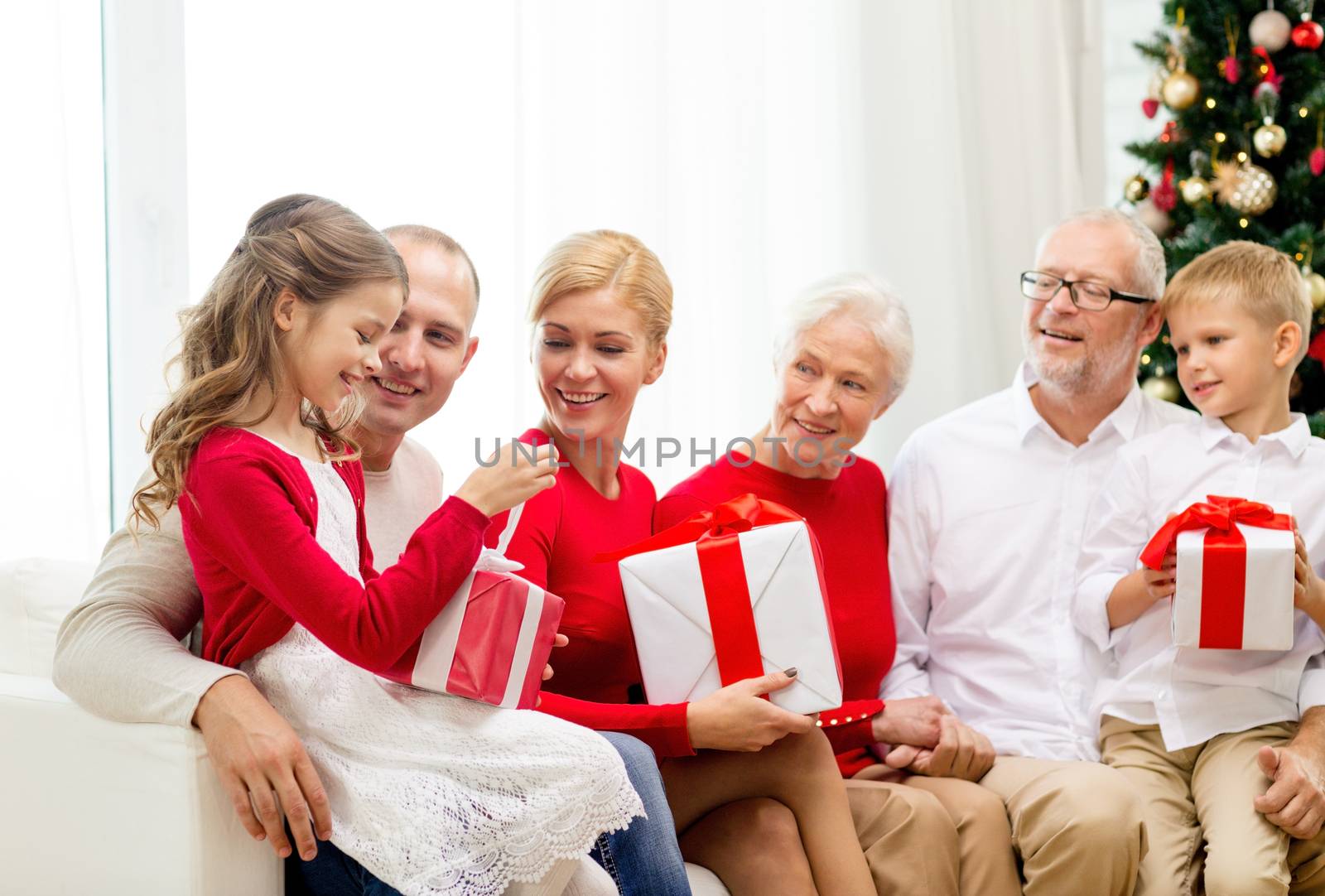 family, holidays, generation, christmas and people concept - smiling family with gift boxes sitting on couch at home