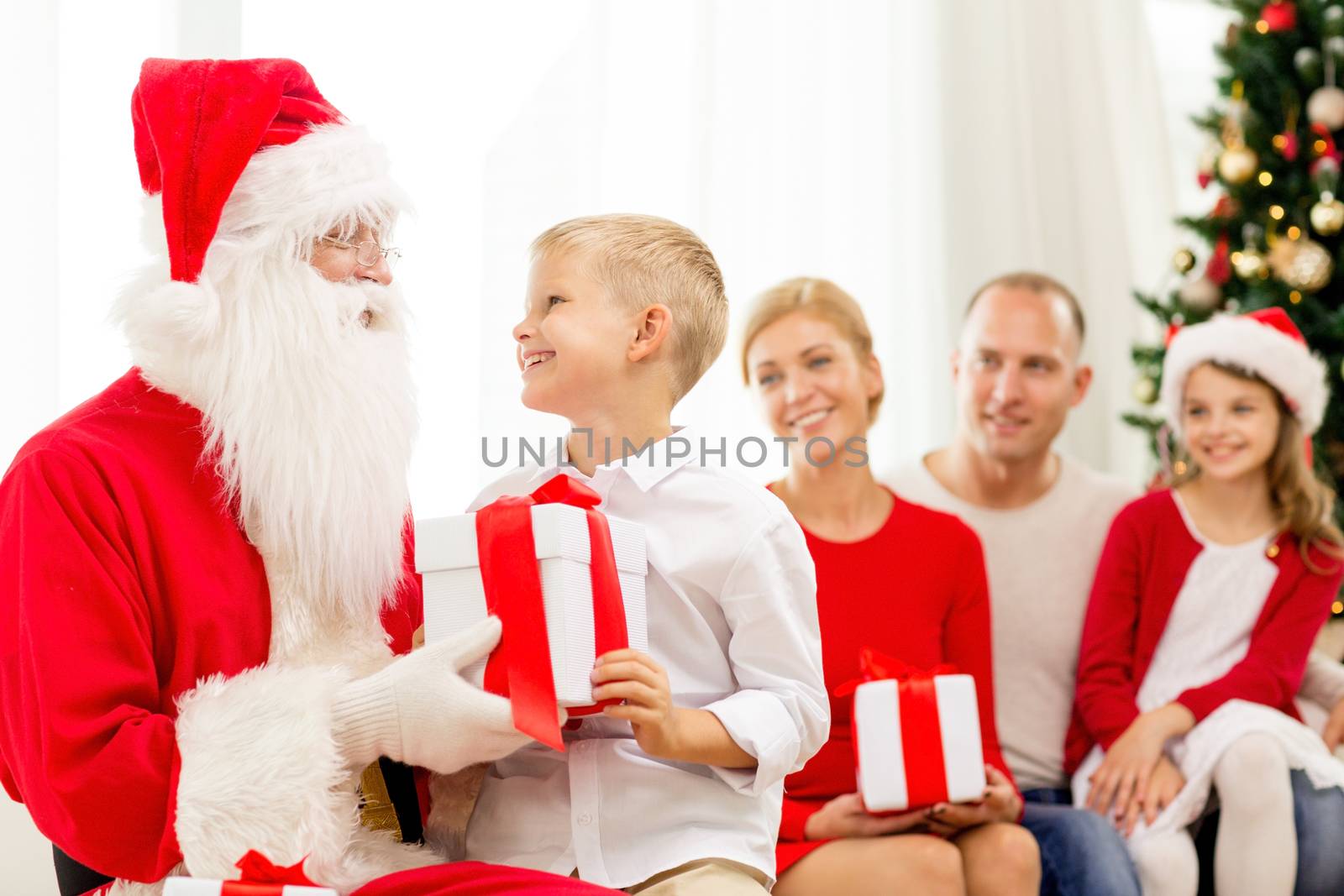 family, holidays, generation, christmas and people concept - smiling family with santa claus and gift boxes at home