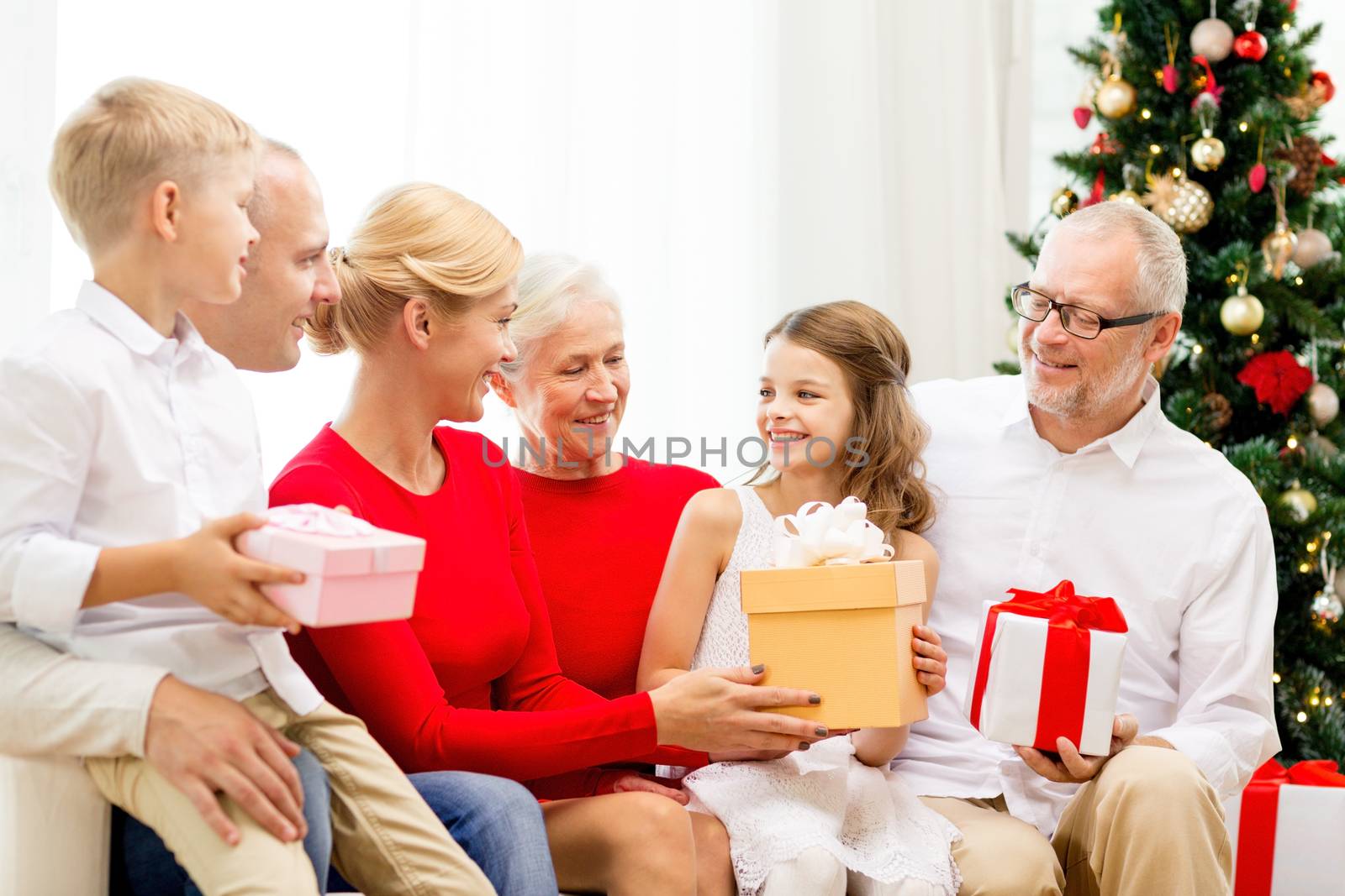 family, holidays, generation, christmas and people concept - smiling family with gift boxes sitting on couch at home