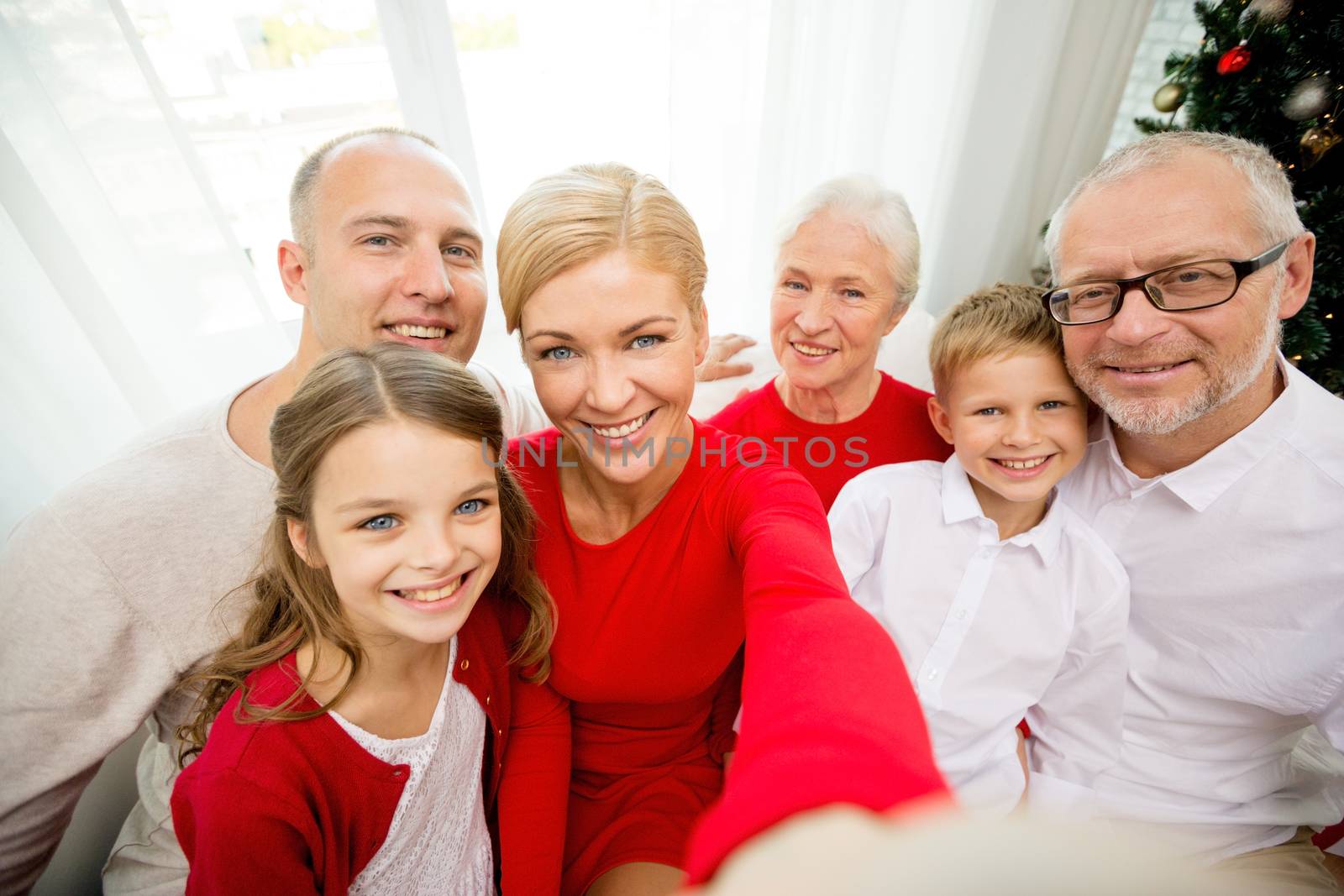 family, holidays, generation, christmas and people concept - smiling family with camera or smartphone making selfie at home