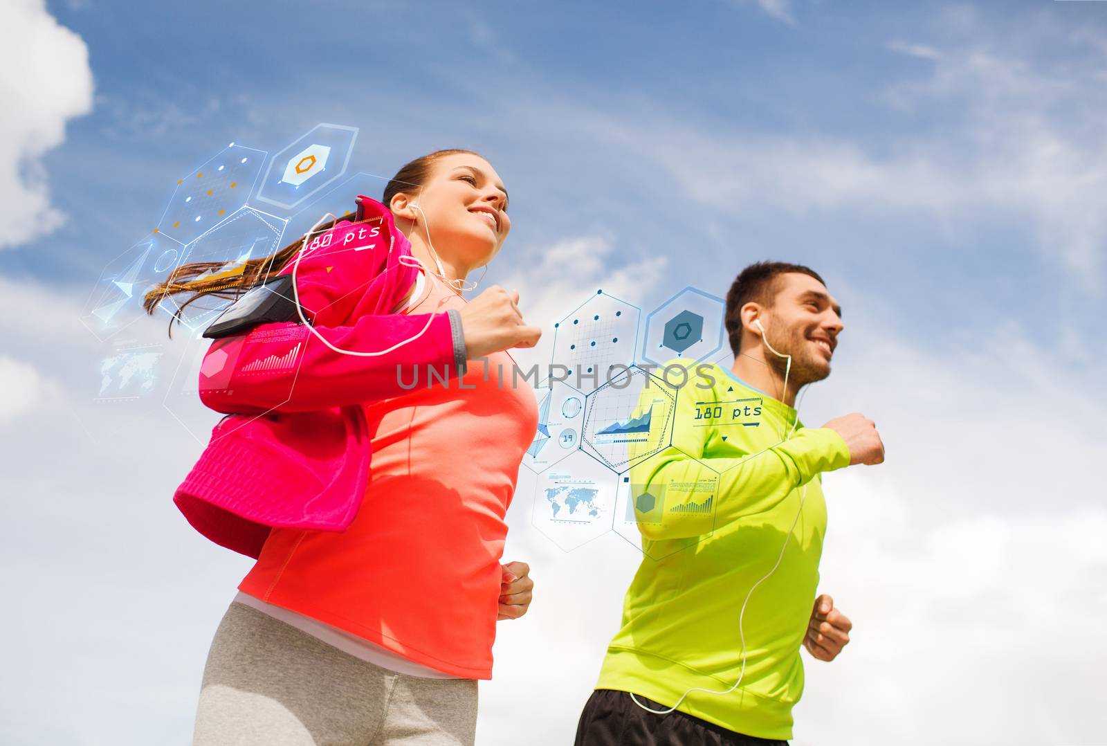 smiling couple with earphones running outdoors by dolgachov