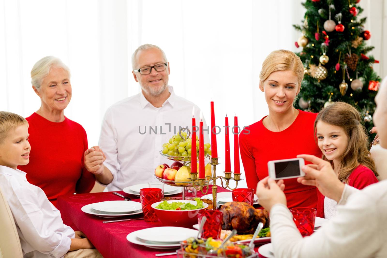 family, holidays, generation, christmas and people concept - smiling family having dinner and making photo with camera at home