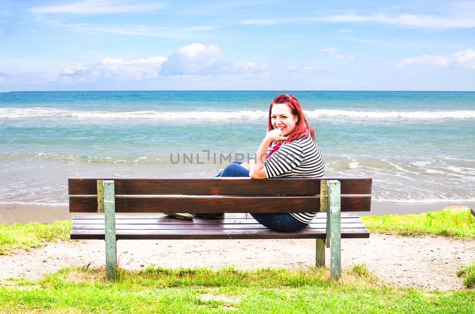 Young Woman sitting alone on a bench overlooking the sea.