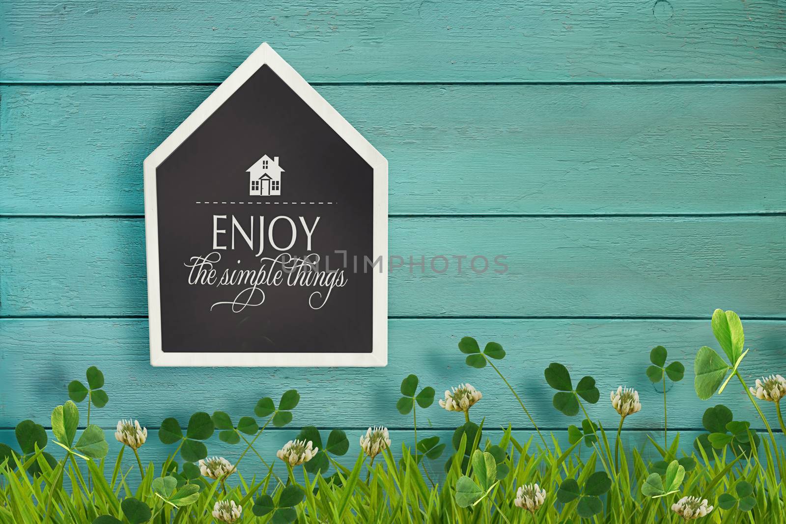 House shaped chalkboard and grass on wooden background